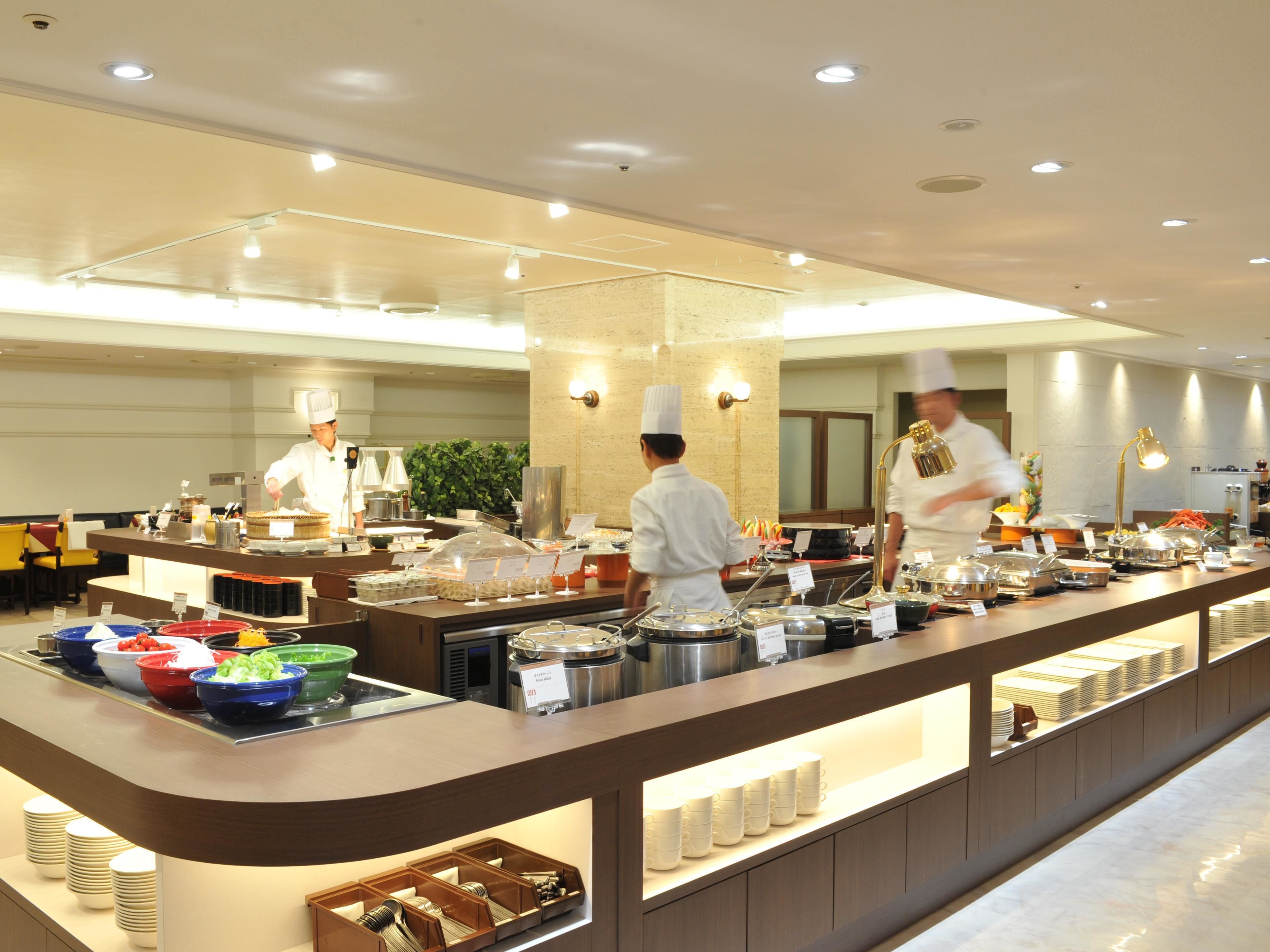A buffet setup with multiple food stations, chefs in uniform, and a well-lit interior.