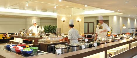 A buffet setup with multiple food stations, chefs in uniform, and a well-lit interior.