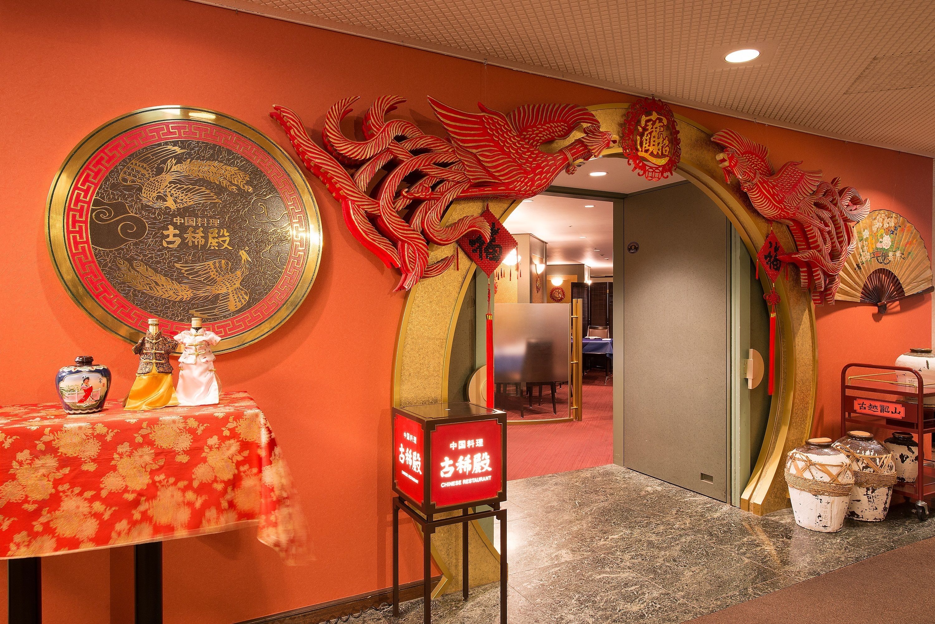 A traditional Chinese restaurant interior with a red and gold color scheme, a decorative dragon archway, and a sign indicating it is a Chinese restaurant.