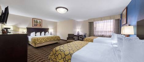 A hotel room with two beds, a desk, a chair, and a TV.