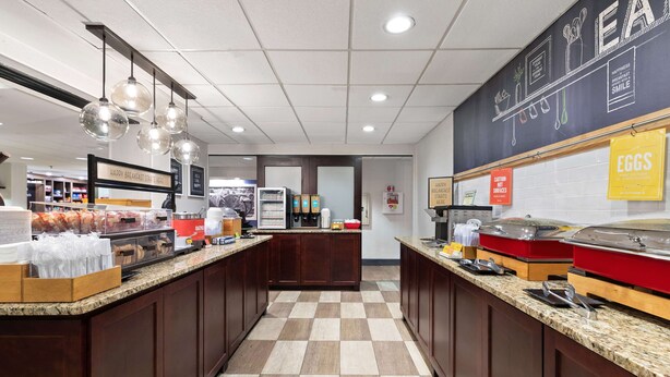 A breakfast bar with checkered flooring, wooden cabinets, and hanging light fixtures.