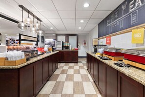Enjoy a delicious breakfast in our inviting breakfast area, featuring a central serving counter with a variety of pastries and beverages.