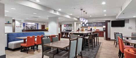 Un restaurante moderno con cabinas y mesas, una zona de bar y una cocina al fondo.