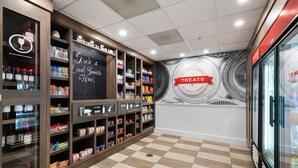 A snack bar with shelves stocked with various snacks and drinks, a chalkboard with a welcome message, and a wall with a 'Treats' sign.