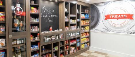A store with shelves stocked with snacks, drinks, and toiletries. A sign reads "Grab a Local Favorite Hero! Welcome to rock hill."