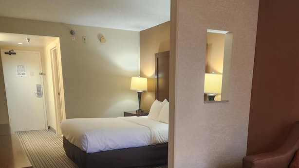 A hotel room with a bed, bedside table, lamp, and a chair. - Best Western Chocolate Inn at the Park (Hummelstown)
