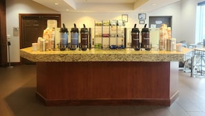 A hotel reception area with a granite counter, multiple beverage dispensers, and a coffee machine. - Best Western Chocolate Inn at the Park (Hummelstown)