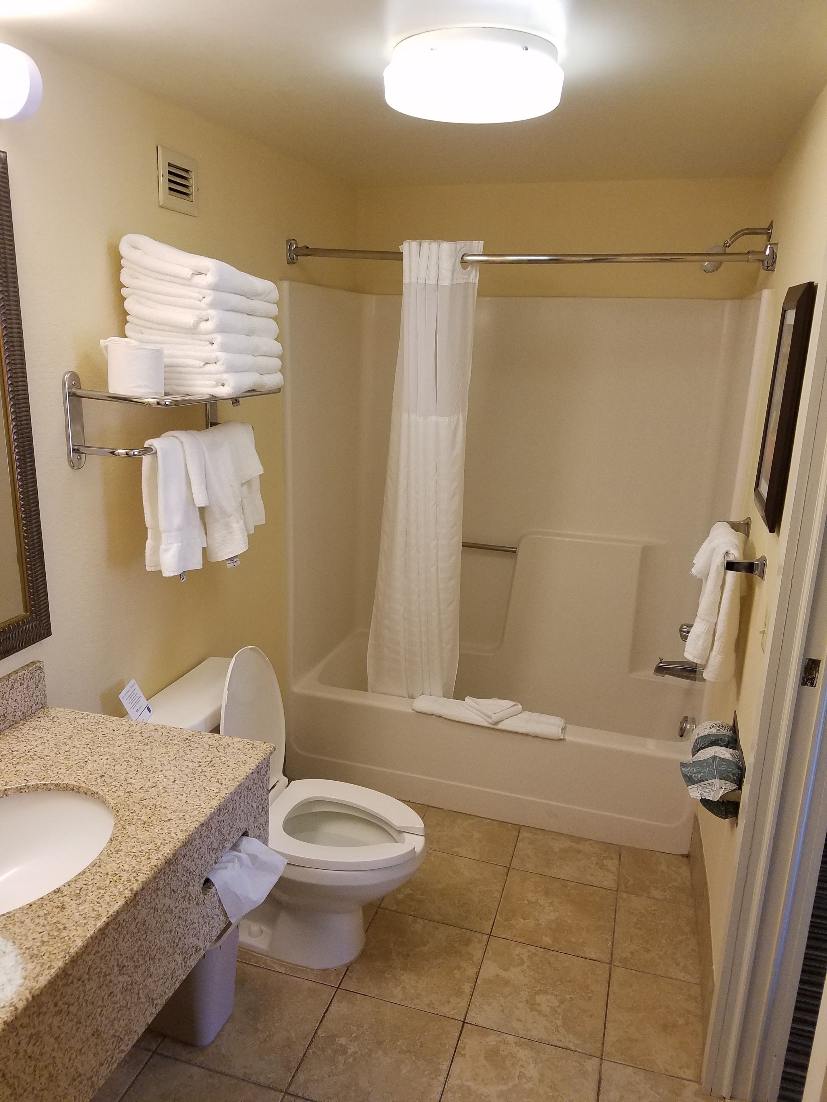 A bathroom with a sink, toilet, and bathtub. There are towels and a shower curtain.