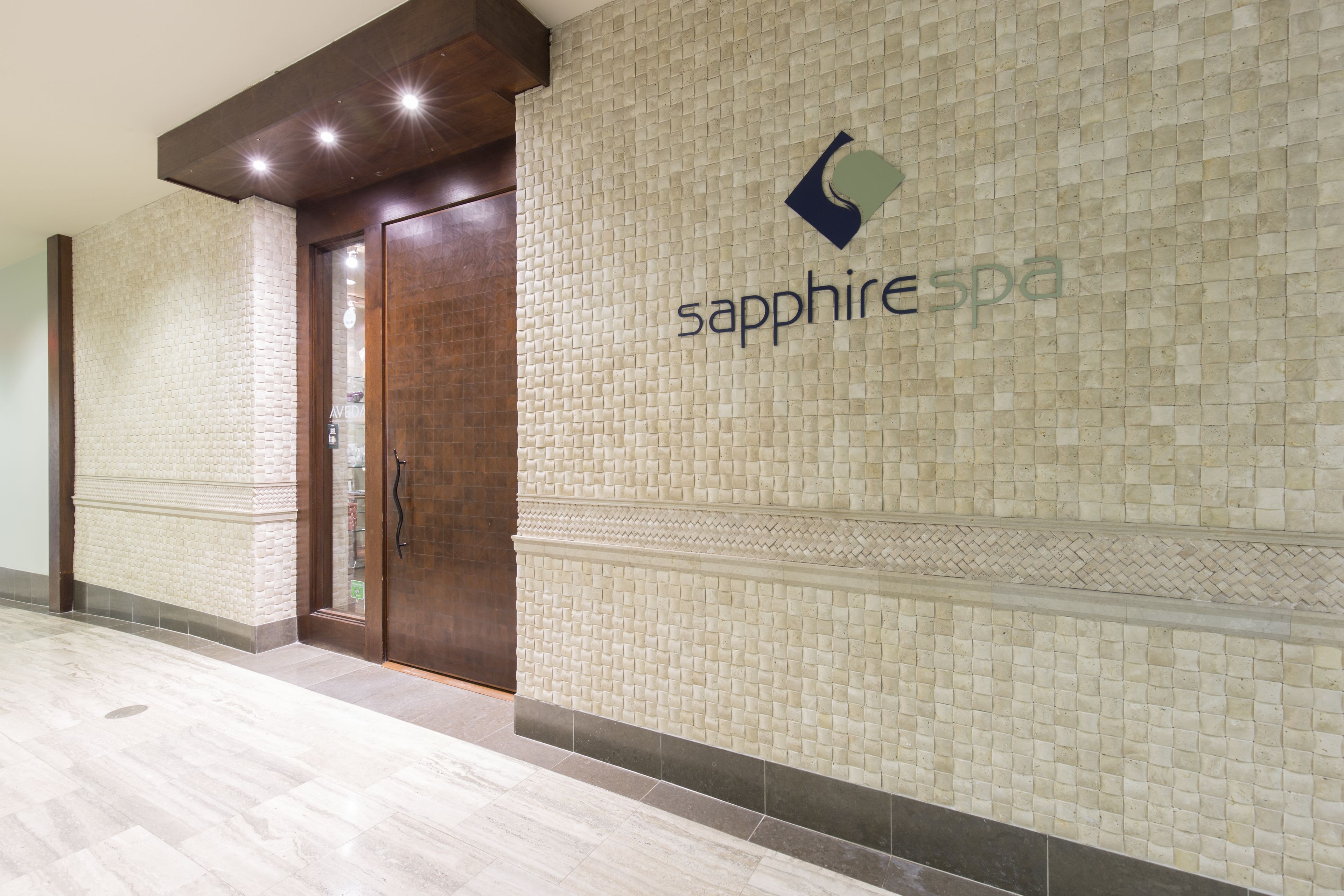 A hallway with a tiled wall, a wooden door, and a logo for 'sapphire spa'.