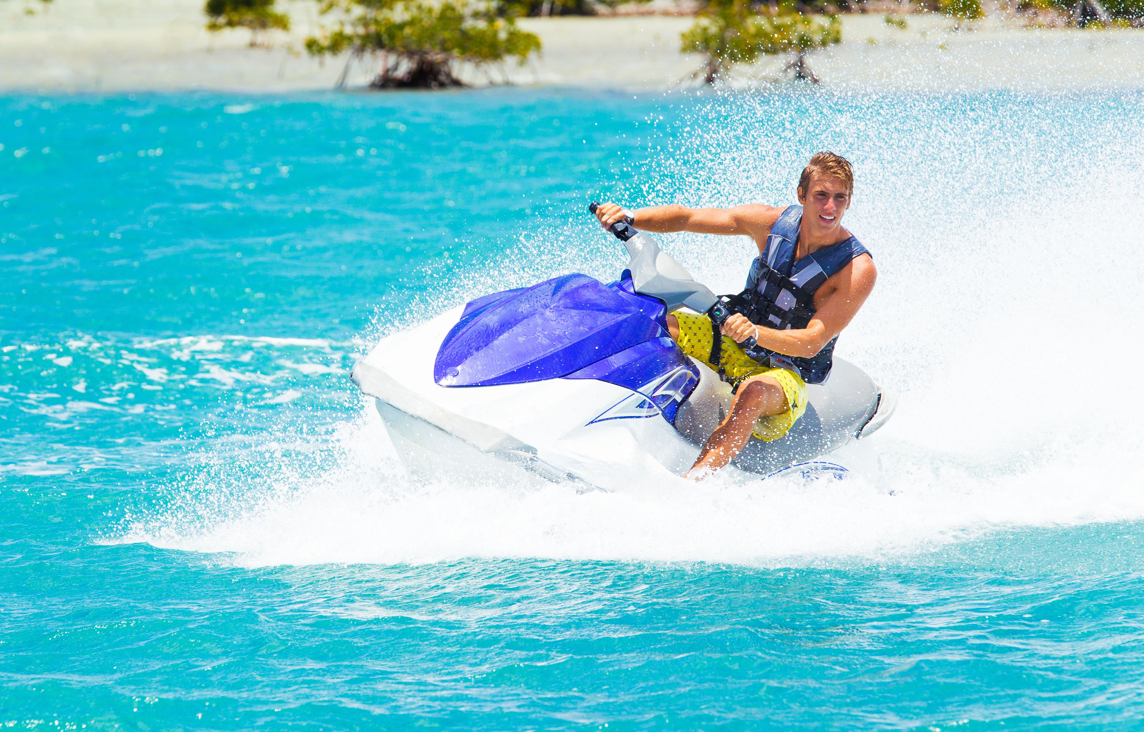 A person riding a jet ski on a clear blue body of water.