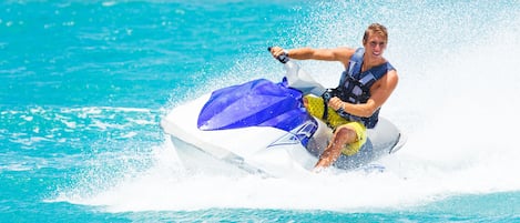 A person riding a jet ski on a clear blue body of water.
