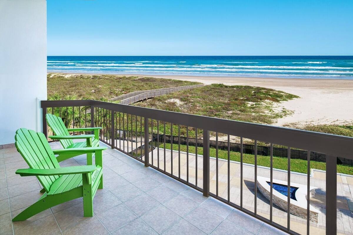 A balcony with a view of the beach and ocean.