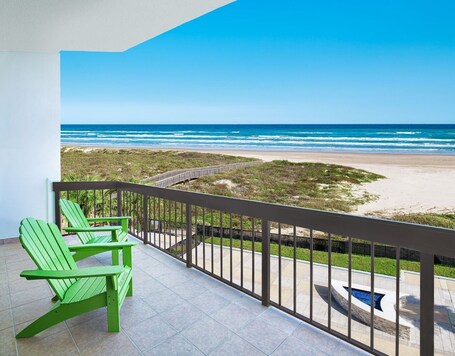 A balcony with a view of the beach and ocean.