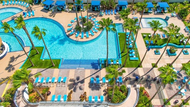 Un resort con varias piscinas, tumbonas y palmeras.