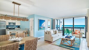 A spacious living area with a dining set, a sofa, and a view of the ocean.