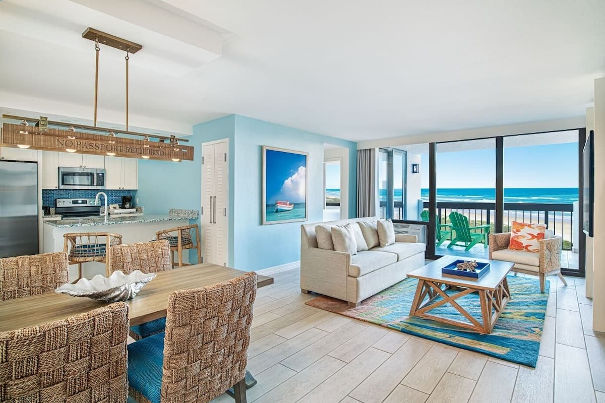 A spacious living area with a dining set, a sofa, and a view of the ocean.