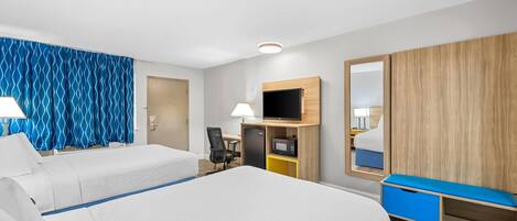 A hotel room with two beds, a desk with a chair, a TV, and a wardrobe.