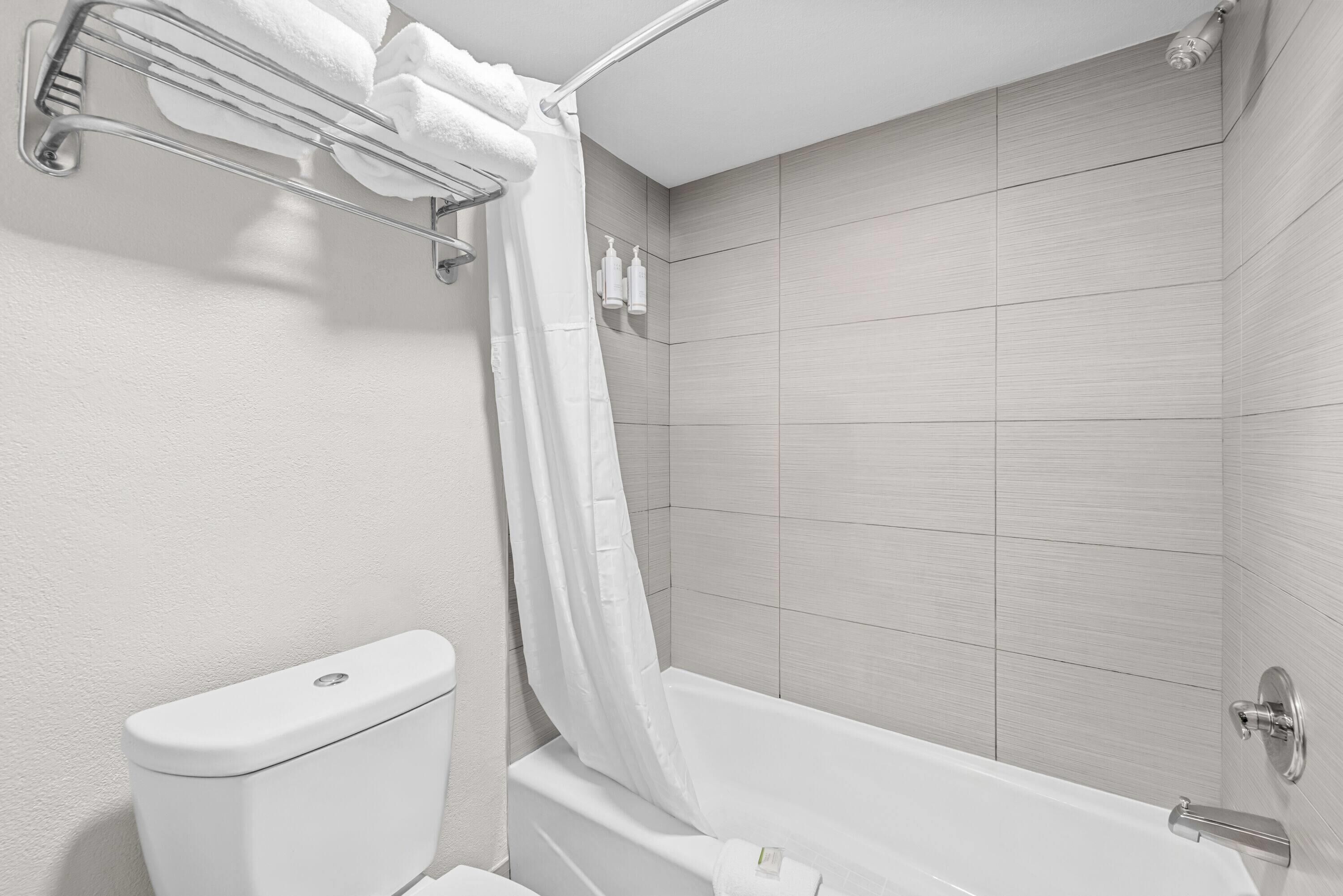 A modern bathroom with a toilet, bathtub, and shower curtain.