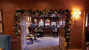 A bar area with a Christmas arch, patterned carpet, and a seating area with a table and chairs.