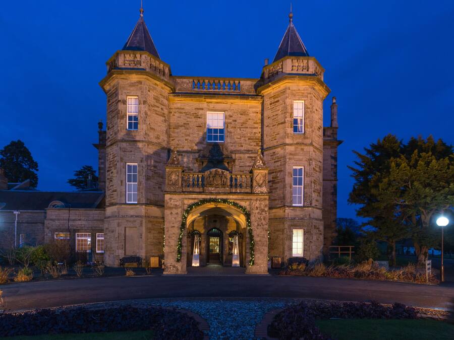 A historic stone building with a central entrance, two towers, and a well-lit facade.