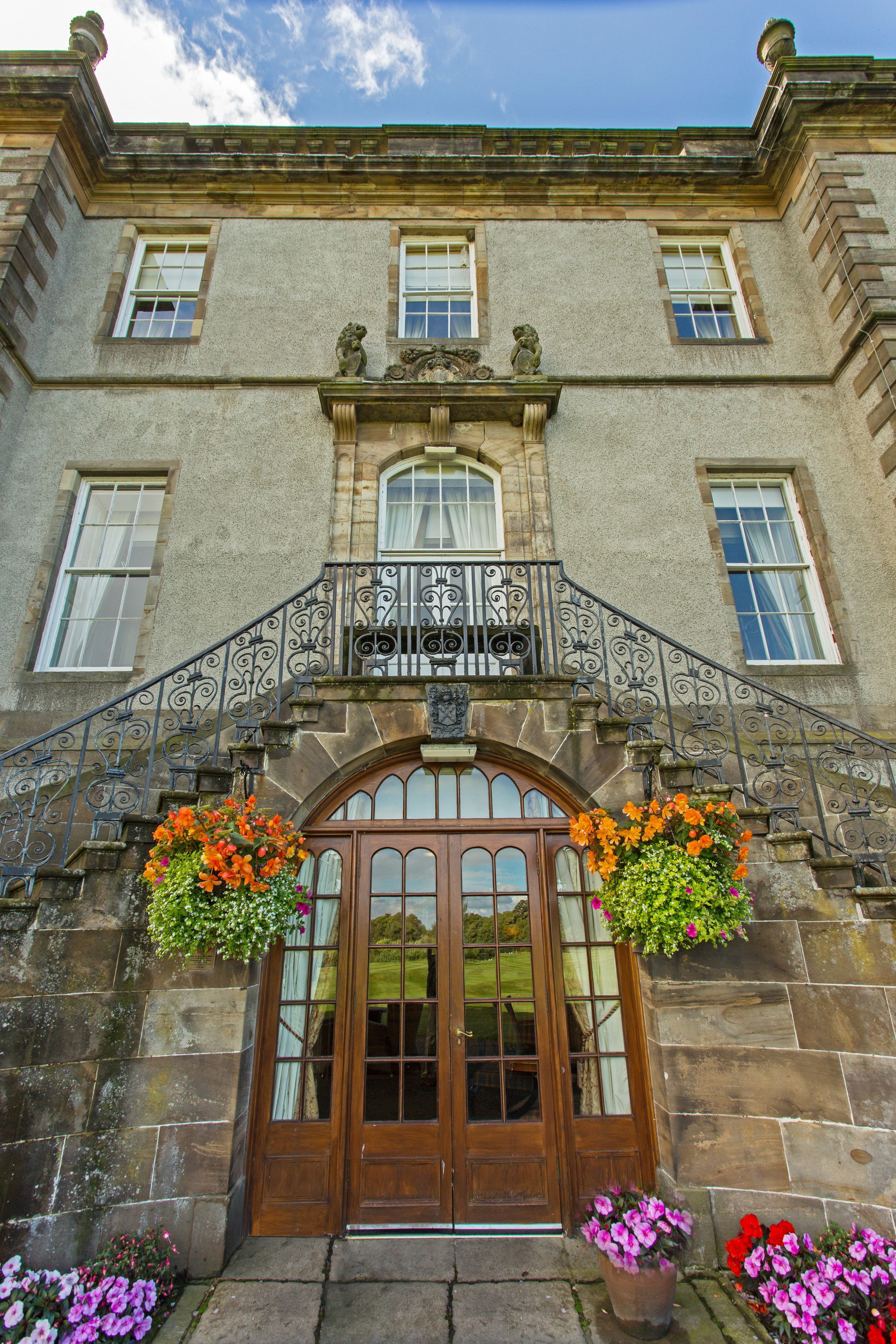 A historic building with a prominent entrance, stone facade, and decorative ironwork.