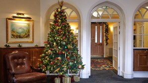 A grand lobby with a large Christmas tree, a leather armchair, and a framed picture on the wall.