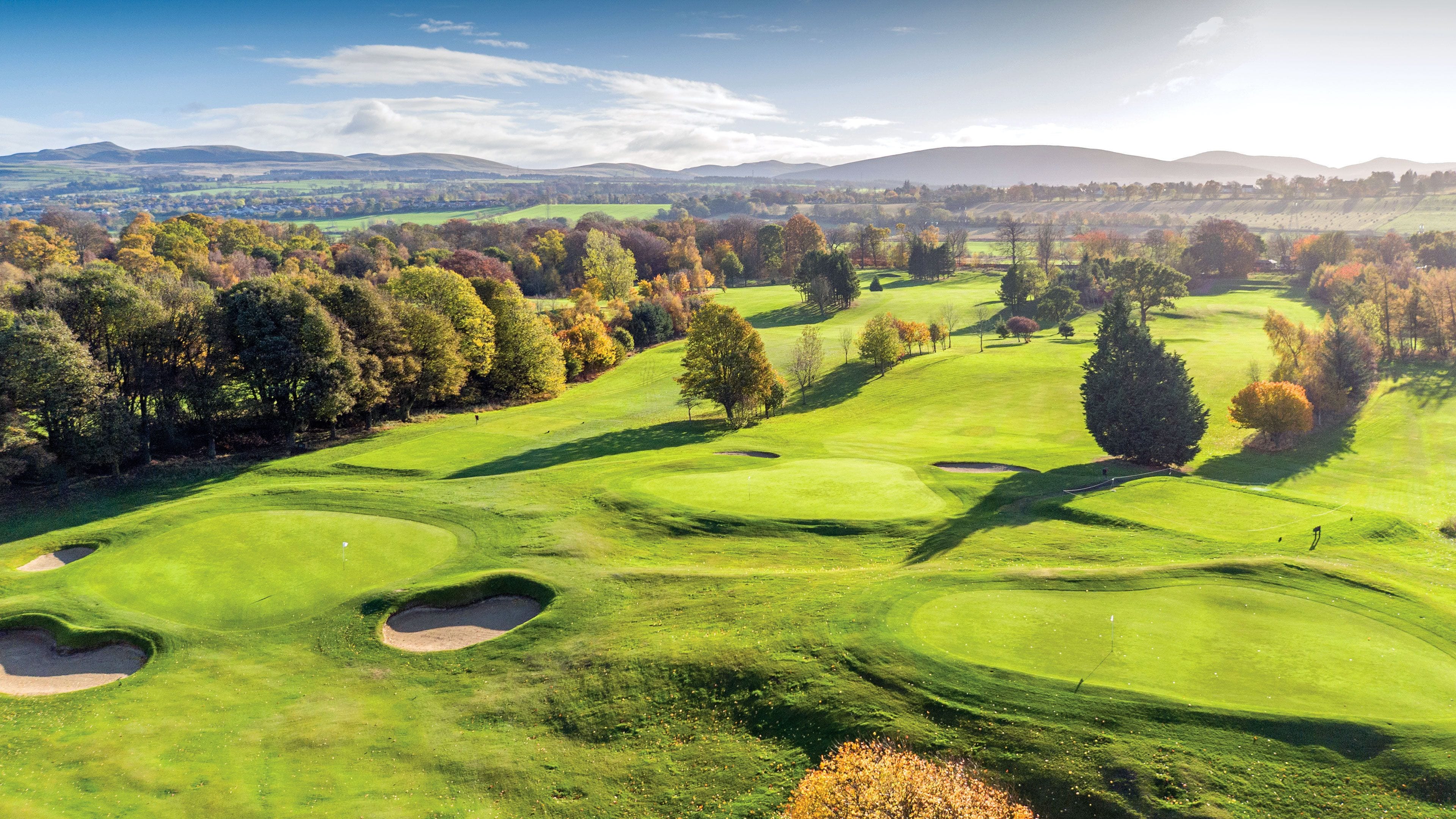 A golf course with multiple bunkers and trees.