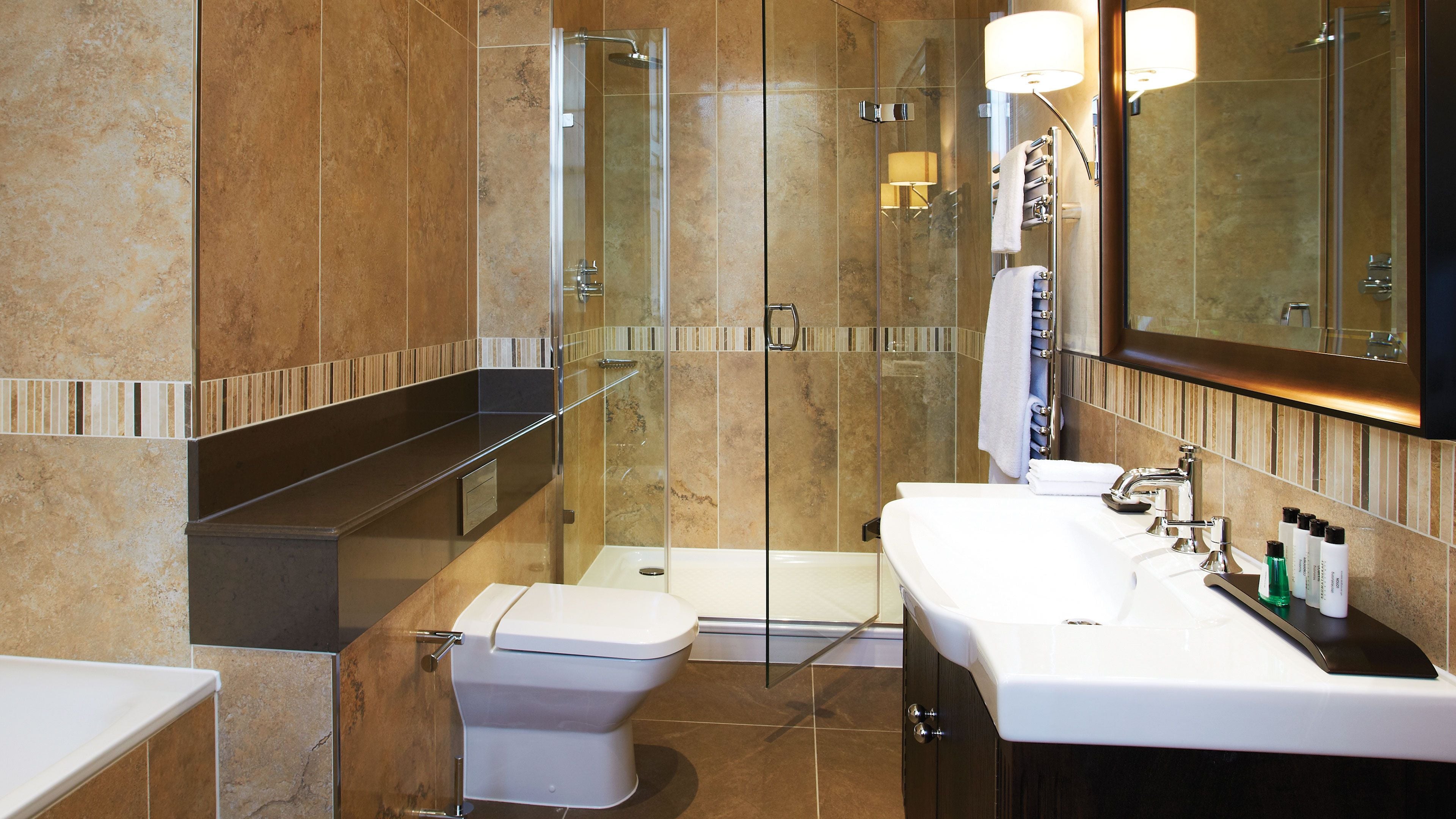 A modern bathroom with a glass-enclosed shower, a white toilet, and a vanity with a mirror.
