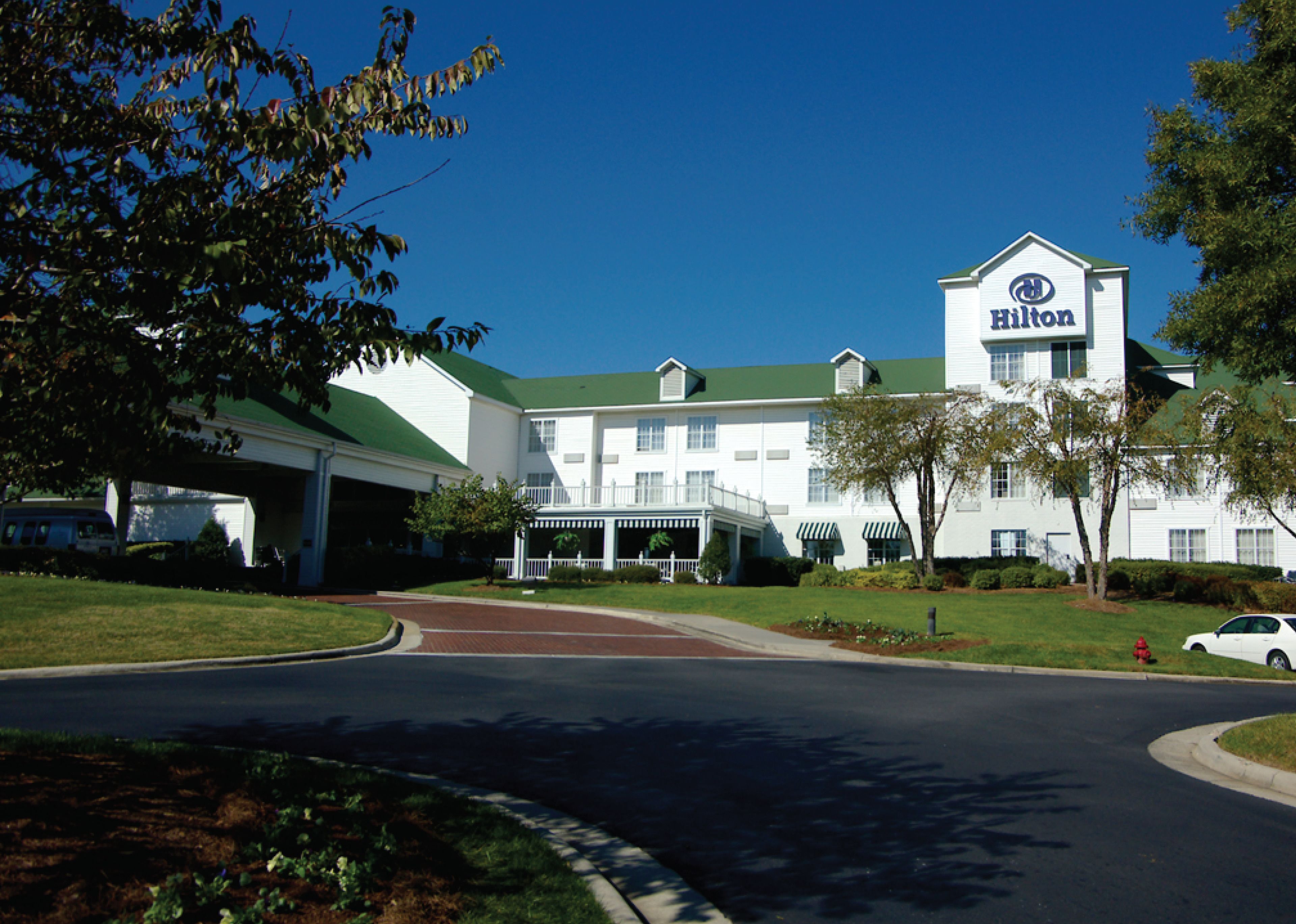 A large, white, multi-story hotel with a green roof and a prominent Hilton sign.