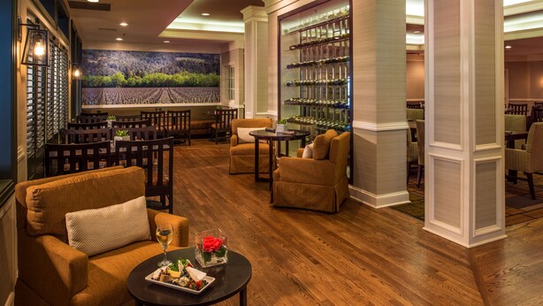 A lobby with a bar area, seating, and a wine display.