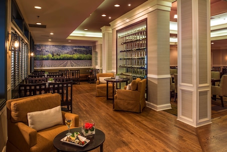 A lobby with a bar area, seating, and a wine display.