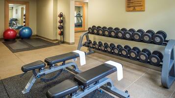 A gym with weightlifting equipment, exercise balls, and a treadmill.