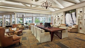 A spacious lounge with leather sofas, a long dining table, and a waterfall mural.