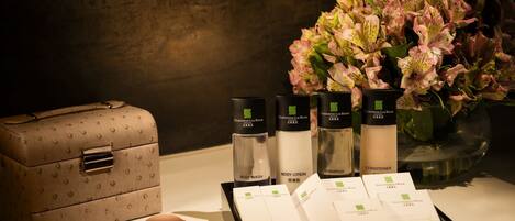 A set of toiletries including body wash, lotion, and conditioner, a handbag, and a vase with flowers.