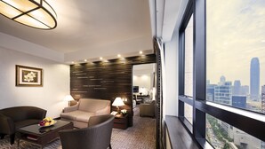 Une chambre d’hôtel moderne avec vue sur la ville, comprenant un canapé, une table basse et un coin repas.