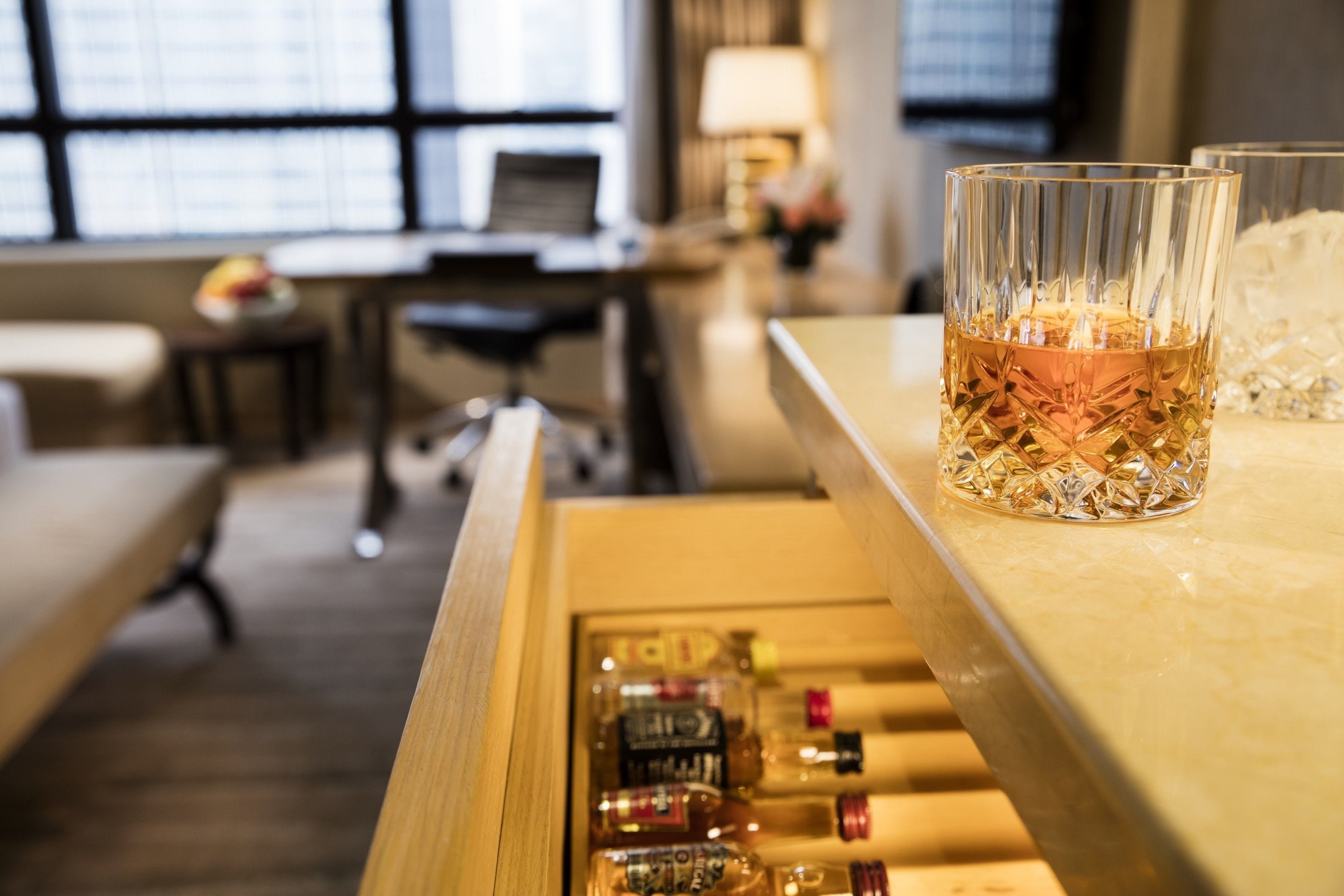 Angolo bar con un bicchiere di whisky e diverse bottiglie di liquori.