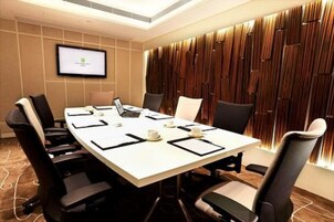 A conference room with a long table, six chairs, a laptop, and a presentation screen.