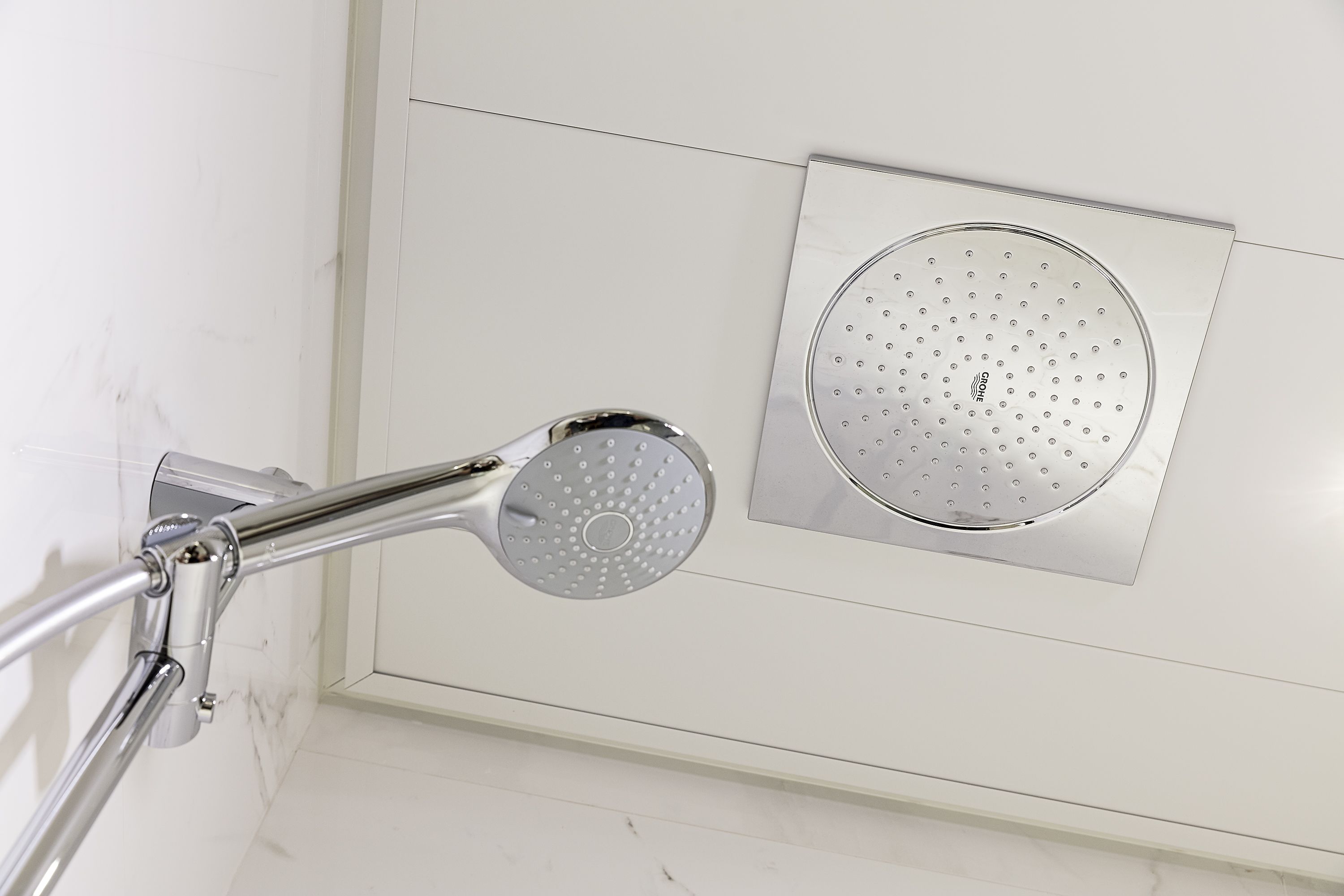 A modern shower with a handheld showerhead and a fixed wall-mounted showerhead.