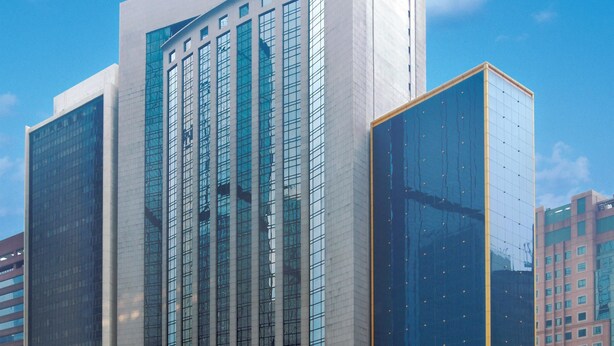 Un moderno edificio de gran altura con ventanas de vidrio reflectante y un llamativo borde amarillo.