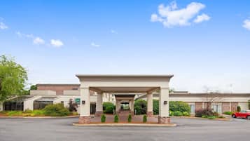 Enter a stylish hotel with a modern design, flanked by brick pillars and lush greenery.
