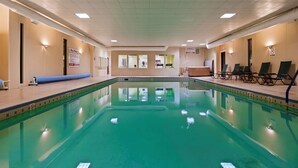 Une piscine à l’eau claire, entourée de chaises longues et d’un espace d’accueil.