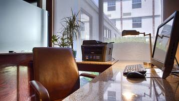 A home office with a desk, chair, computer, printer, and a potted plant.