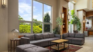 Una sala de estar moderna con un sofá modular, una mesa de centro y un ventanal con vistas a zonas verdes.