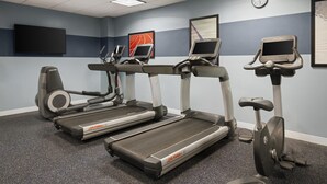 Un gimnasio con cintas de correr, una bicicleta estática y una máquina de remo.