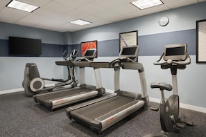 Een fitnessruimte met loopbanden, een hometrainer en een roeimachine.