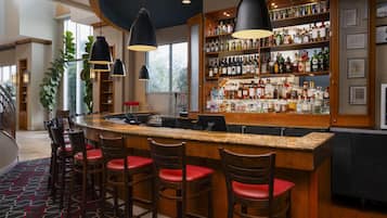A bar area with a counter, stools, and a variety of bottles.