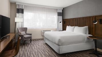 Une chambre d’hôtel avec un lit, un bureau, une chaise, une télévision et une lampe.