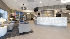 A modern reception area with a white reception desk, comfortable seating, and a large wall mural.