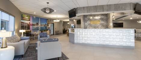 A modern reception area with a white reception desk, comfortable seating, and a large wall mural.