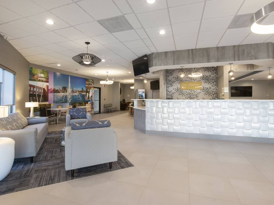 A modern reception area with a white reception desk, comfortable seating, and a large wall mural.